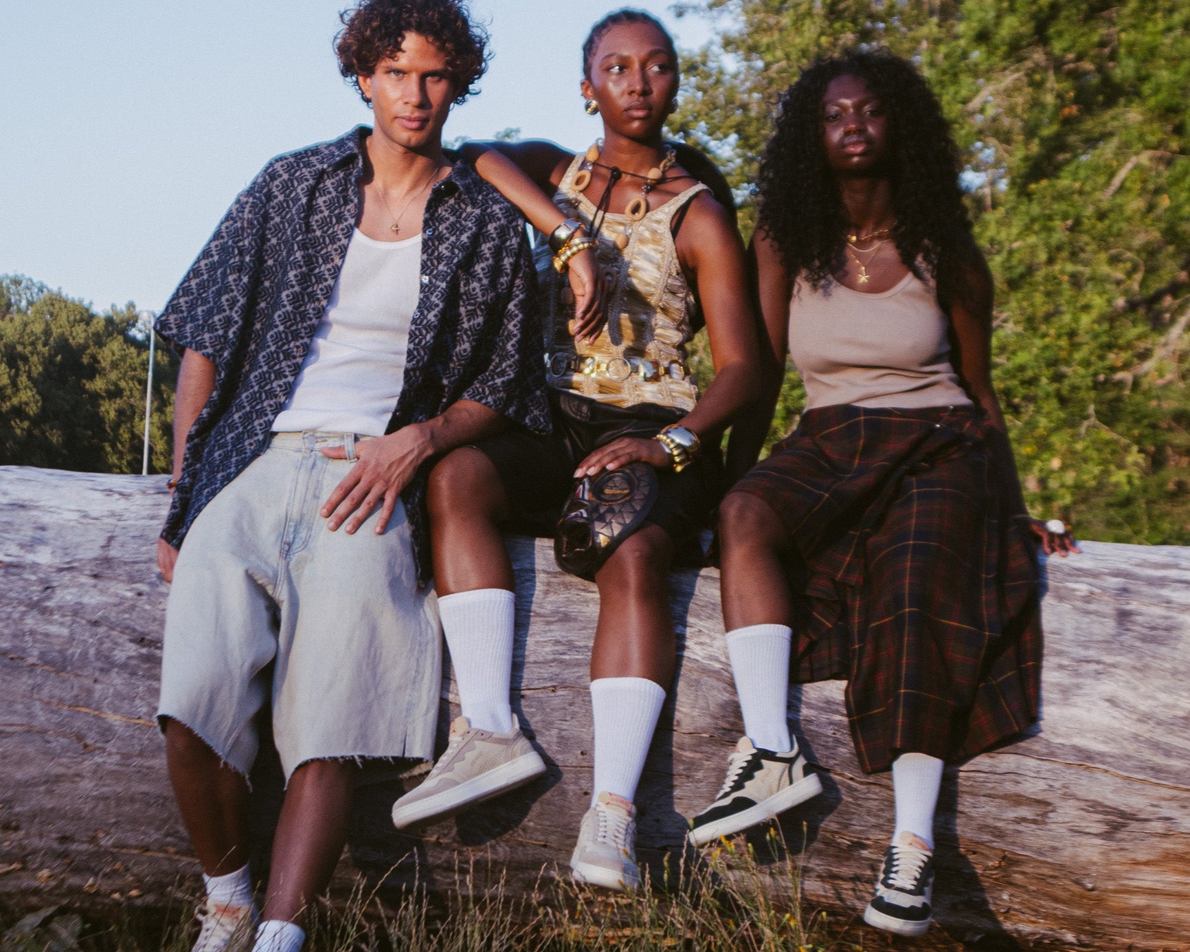 Three people sitting on a log outdoors with trees in the background